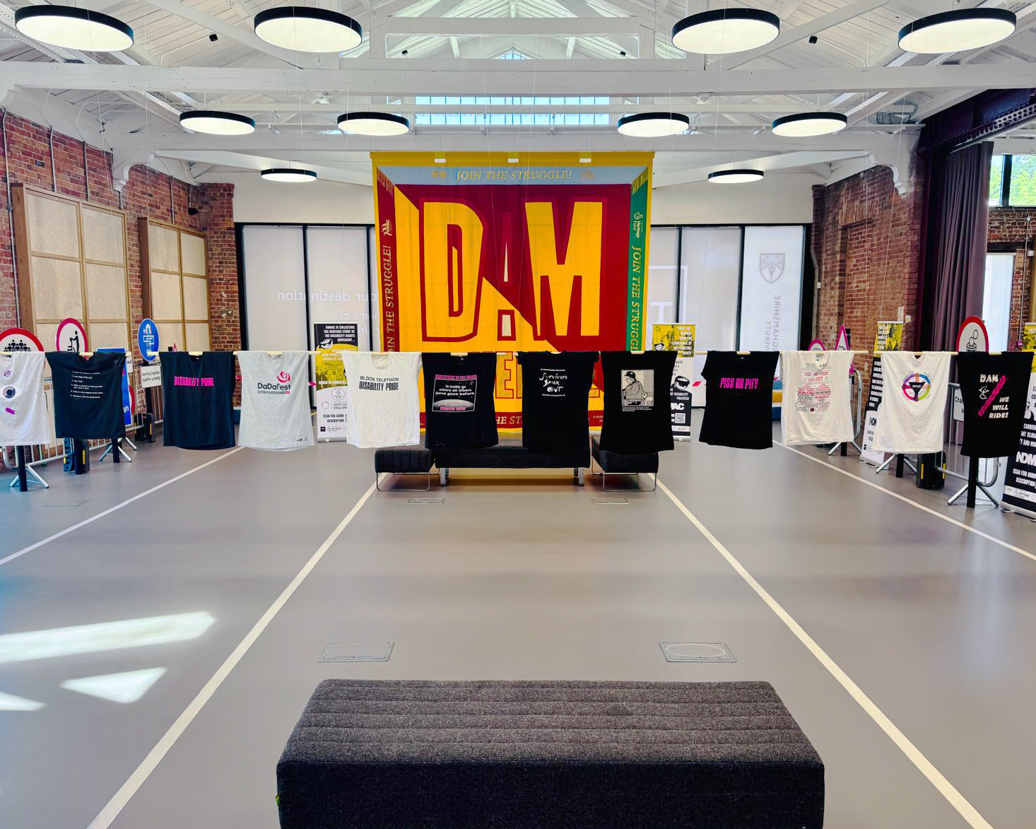 Commercial dark grey sustainable resin floor with railway tracks in a light grey. In the background is a banner and t-shirts hanging on a line