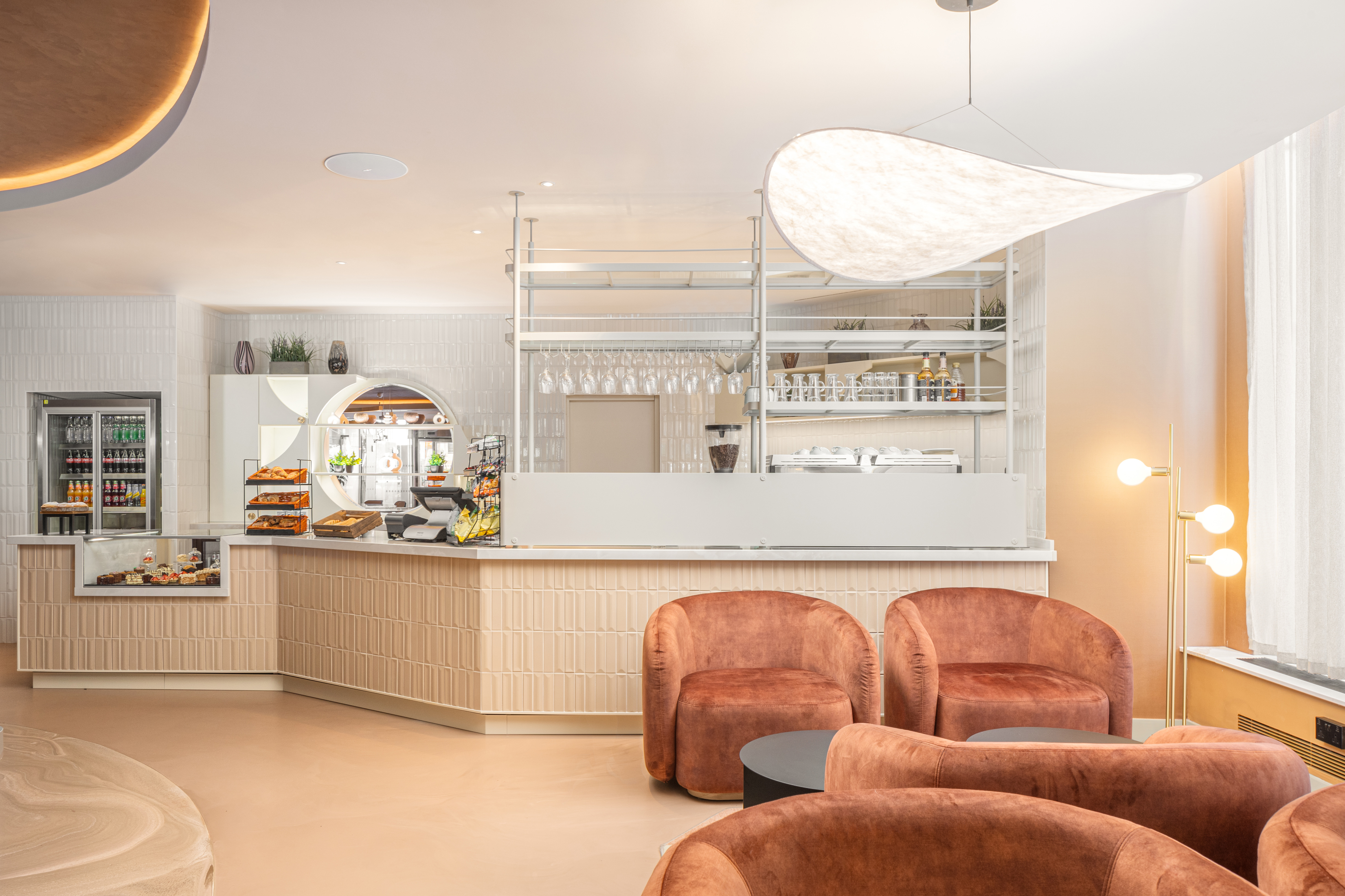 A corner reception desk with ligh resin flooring and red chairs
