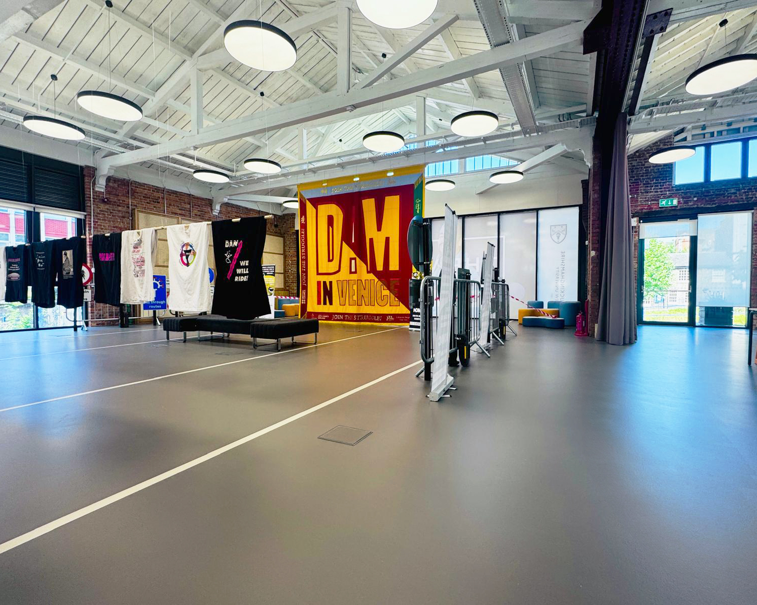 Sideway view of commercial dark grey sustainable resin floor with railway tracks in a light grey. Banner and t-shirts hanging in the background