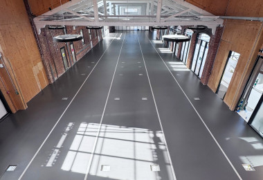 Dark grey sustainable commercial resin floor in large open space with pale grey train tracks