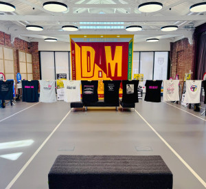 Commercial dark grey sustainable resin floor with railway tracks in a light grey. In the background is a banner and t-shirts hanging on a line