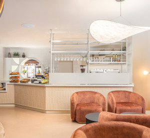 A corner reception desk with ligh resin flooring and red chairs