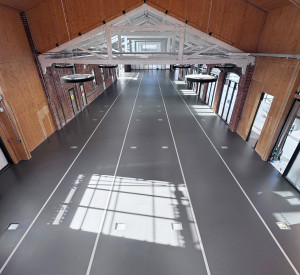 Commercial dark grey sustainable resin floor with railway tracks in a light grey. View of the entire floor from a height