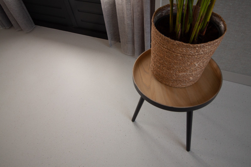 Grey resin terrazzo floor with a side table and plant