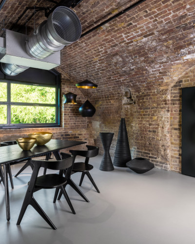 Light grey commercial resin flooring with a dining table and chairs, and an exposed brick wall