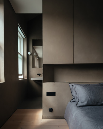 A bedroom with resin walls and joinery throughout